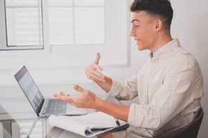Happy young man teenager smiling and talking in video conference studying