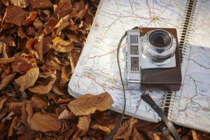 Still life in the autumn forest with camera and map. Travel
