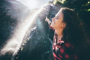 Young happy girl enjoying the waterfall.